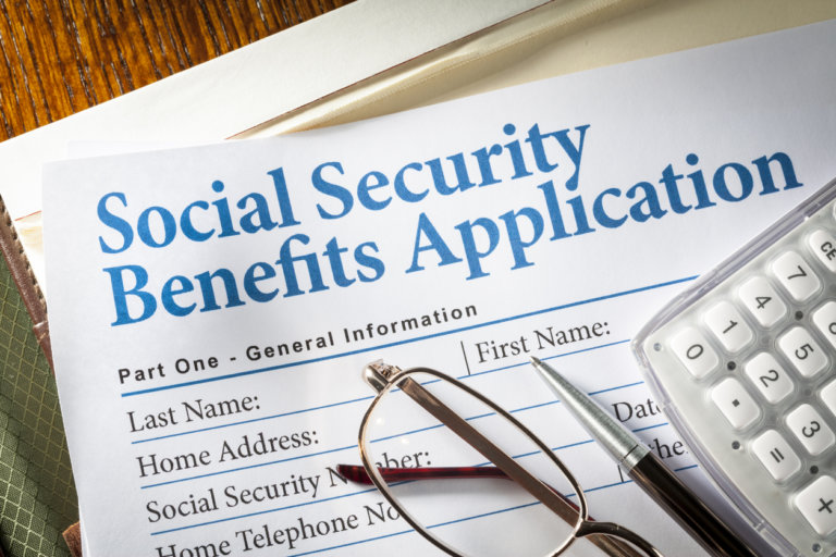 Social Security Benefits form with pen, glasses, and calculator